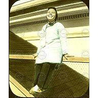 Chinese woman sitting on a railing, she has a big smile on her face<br/>