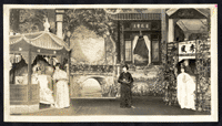 man in a pavilion is served tea by a maid, a woman in a cape stands by a trellised arbor, staged at the Great Star Theatre /